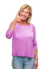 Middle age blonde woman over isolated background doing happy thumbs up gesture with hand. Approving expression looking at the camera with showing success.