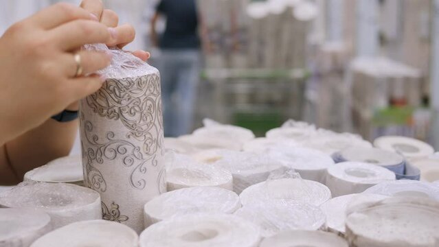 Close-up of a woman choosing the right roll of wallpaper in a hardware store. Goods for repair. 