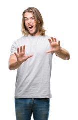 Fototapeta na wymiar Young handsome man with long hair over isolated background afraid and terrified with fear expression stop gesture with hands, shouting in shock. Panic concept.