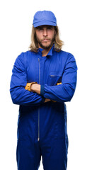 Young handsome mechanic man with long hair over isolated background skeptic and nervous, disapproving expression on face with crossed arms. Negative person.