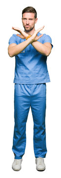 Handsome doctor man wearing medical uniform over isolated background Rejection expression crossing arms doing negative sign, angry face