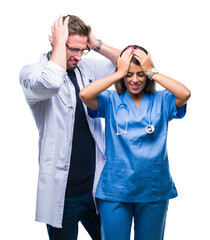 Fototapeta premium Young couple of doctor and surgeon over isolated background suffering from headache desperate and stressed because pain and migraine. Hands on head.