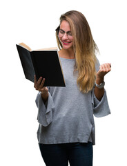 Young beautiful blonde woman reading a book over isolated background screaming proud and celebrating victory and success very excited, cheering emotion