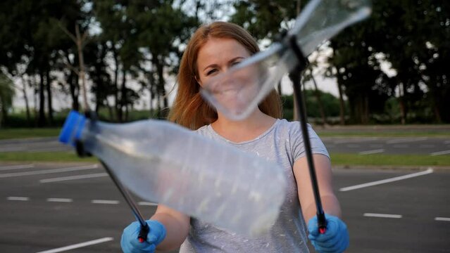 Portrait of a female volunteer with tongs for collecting plastic garbage in her hands. The concept of volunteering and garbage collection. Environmental protection.