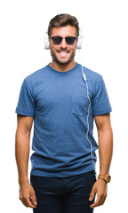 Young handsome man wearing headphones listening to music over isolated background with a happy and cool smile on face. Lucky person.