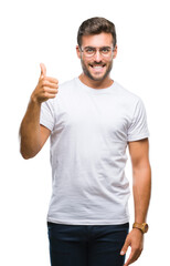 Young handsome man wearing glasses over isolated background doing happy thumbs up gesture with hand. Approving expression looking at the camera with showing success.