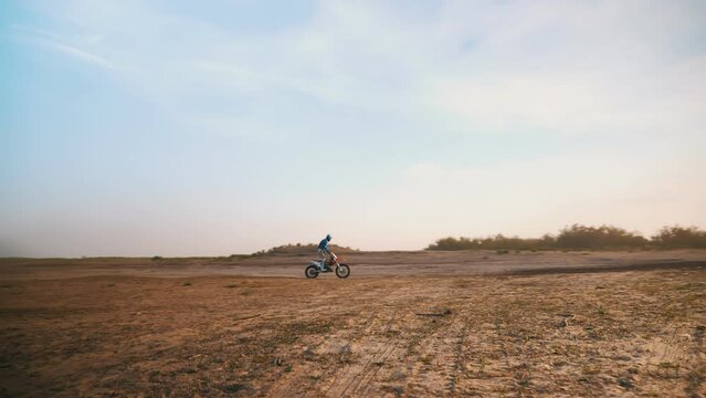 A motorcyclist drives through a sandy field. beautiful panorama. Slow motion.
