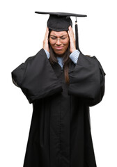 Young hispanic woman wearing graduated cap and uniform suffering from headache desperate and stressed because pain and migraine. Hands on head.