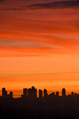Urban silhouette of buildings on sunset sky background