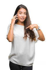 Young beautiful arab woman talking on the phone over isolated background with surprise face pointing finger to himself