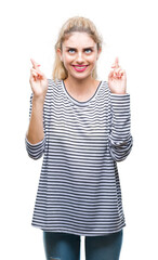 Fototapeta na wymiar Young beautiful blonde woman wearing stripes sweater over isolated background smiling crossing fingers with hope and eyes closed. Luck and superstitious concept.