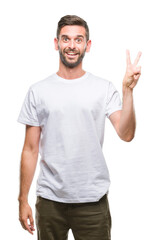 Young handsome man over isolated background smiling with happy face winking at the camera doing victory sign. Number two.