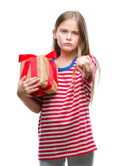 Young beautiful girl giving christmas or valentine gift over isolated background pointing with finger to the camera and to you, hand sign, positive and confident gesture from the front