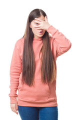 Fototapeta premium Young Chinese woman over isolated background wearing sport sweathshirt peeking in shock covering face and eyes with hand, looking through fingers with embarrassed expression.
