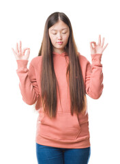 Young Chinese woman over isolated background wearing sport sweathshirt relax and smiling with eyes closed doing meditation gesture with fingers. Yoga concept.