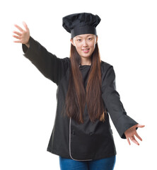 Young Chinese woman over isolated background wearing chef uniform looking at the camera smiling with open arms for hug. Cheerful expression embracing happiness.