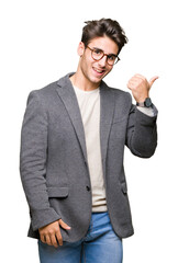 Young business man wearing glasses over isolated background smiling with happy face looking and pointing to the side with thumb up.