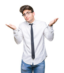Young business man wearing glasses over isolated background clueless and confused expression with arms and hands raised. Doubt concept.