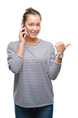 Young beautiful caucasian woman talking on smartphone over isolated background pointing and showing with thumb up to the side with happy face smiling