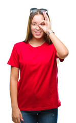 Young beautiful caucasian woman wearing sunglasses over isolated background doing ok gesture with hand smiling, eye looking through fingers with happy face.