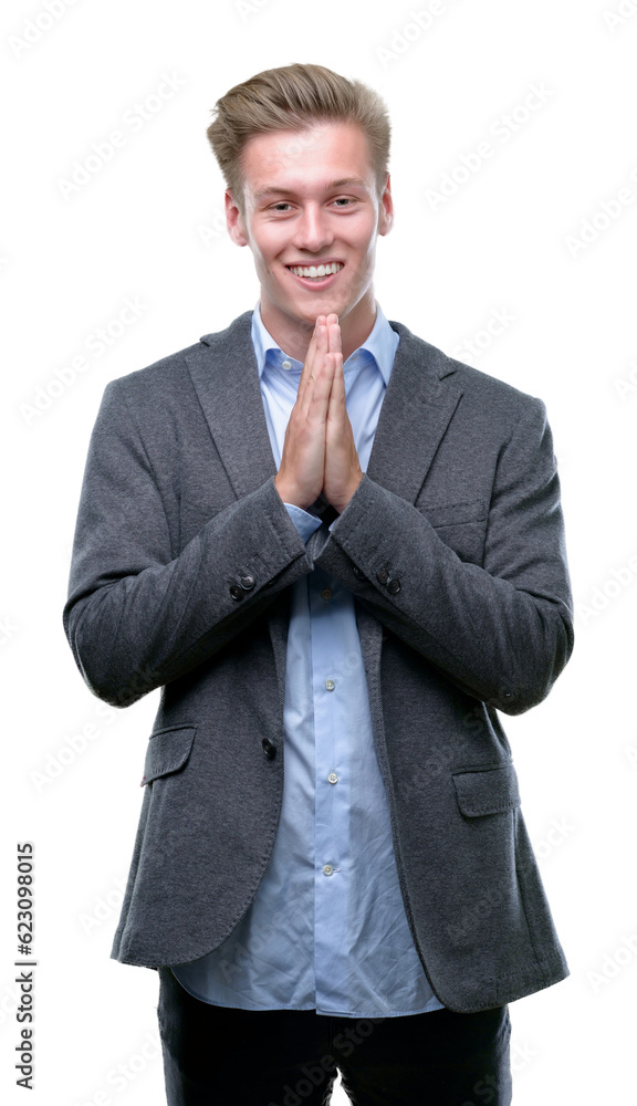 Sticker Young handsome blond business man praying with hands together asking for forgiveness smiling confident.