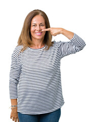 Beautiful middle age woman wearing stripes sweater over isolated background Pointing with hand finger to face and nose, smiling cheerful