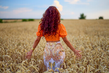 A beautiful woman with long hair posing in a field of wheat. conceptual fashion image.