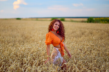 A beautiful woman with long hair posing in a field of wheat. conceptual fashion image.