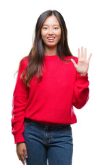 Young asian woman wearing winter sweater over isolated background showing and pointing up with fingers number five while smiling confident and happy.