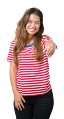 Obraz na płótnie Canvas Young beautiful brunette woman wearing stripes t-shirt over isolated background smiling friendly offering handshake as greeting and welcoming. Successful business.
