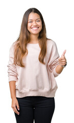 Young beautiful brunette woman wearing pink sweatshirt over isolated background doing happy thumbs up gesture with hand. Approving expression looking at the camera with showing success.
