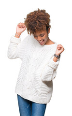 Beautiful young african american woman wearing winter sweater over isolated background Dancing happy and cheerful, smiling moving casual and confident listening to music