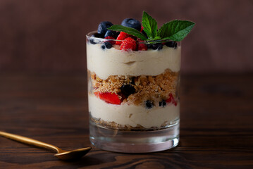 Portion of dessert in a glass with berries, mint, whipped cream and biscuit. Healthy food, vegan, sugar, gluten and lactose free.