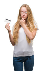 Fototapeta premium Blonde teenager woman holding credit card serious face thinking about question, very confused idea