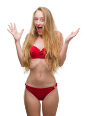 Blonde teenager woman wearing red bikini celebrating crazy and amazed for success with arms raised and open eyes screaming excited. Winner concept