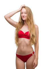Blonde teenager woman wearing red bikini confuse and wonder about question. Uncertain with doubt, thinking with hand on head. Pensive concept.