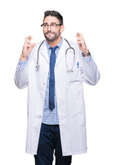 Handsome young doctor man over isolated background smiling crossing fingers with hope and eyes closed. Luck and superstitious concept.