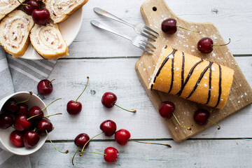 Cherry strudel, on a wooden board, with fresh cherries. On a wooden background