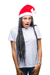 Young braided hair african american girl wearing christmas hat over isolated background afraid and shocked with surprise expression, fear and excited face.