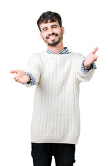 Young handsome man wearing winter sweater over isolated background looking at the camera smiling with open arms for hug. Cheerful expression embracing happiness.