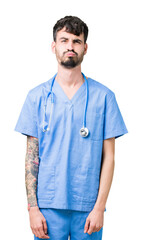 Young handsome nurse man wearing surgeon uniform over isolated background puffing cheeks with funny face. Mouth inflated with air, crazy expression.