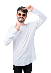 Fototapeta premium Young handsome man wearing sunglasses over isolated background smiling making frame with hands and fingers with happy face. Creativity and photography concept.