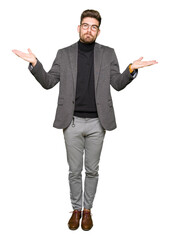 Young handsome business man wearing glasses clueless and confused expression with arms and hands raised. Doubt concept.
