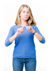 Beautiful young woman wearing blue sweater over isolated background Rejection expression crossing fingers doing negative sign