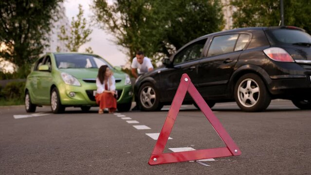 Red emergency stop triangle sign afore Destroyed car in car crash traffic accident on city road. Man driver looking on Smashed broken car in accident. Copy space.