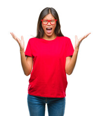 Obraz na płótnie Canvas Young asian woman wearing glasses over isolated background crazy and mad shouting and yelling with aggressive expression and arms raised. Frustration concept.