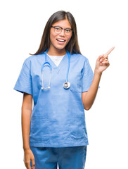 Young asian doctor woman over isolated background with a big smile on face, pointing with hand and finger to the side looking at the camera.