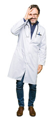 Fototapeta premium Handsome middle age doctor man wearing medical coat doing ok gesture with hand smiling, eye looking through fingers with happy face.