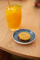 Orange cocktail drink with a cookie at table at cafe