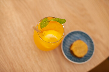 Orange cocktail drink with a cookie at table at cafe